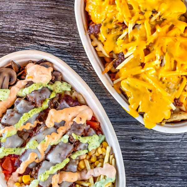 Two Burbowl burger bowls, one with cheese sauce, the other with various toppings and drizzles.